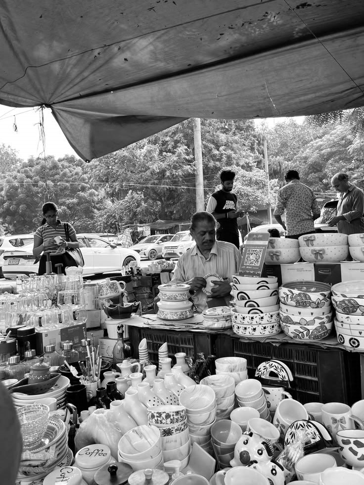 A ceramics vendor at an outdoor Indian craft market, surrounded by handmade pottery